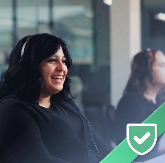 Woman wearing headphones and smiling in an office setting with a green checkmark icon.